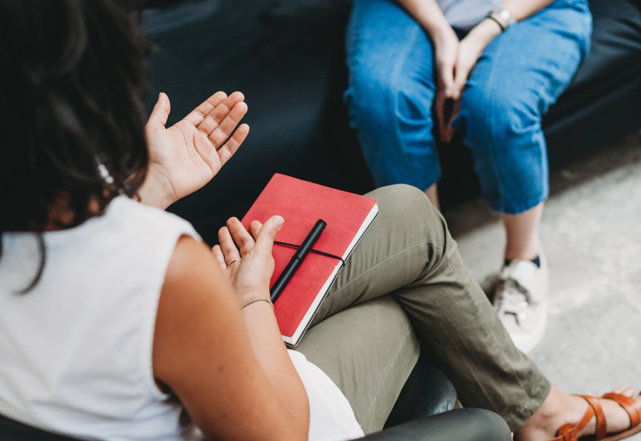 A counsellor and a woman sitting on a chair and couch talking together