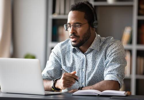 Student wearing headphones working at a desk with a laptop