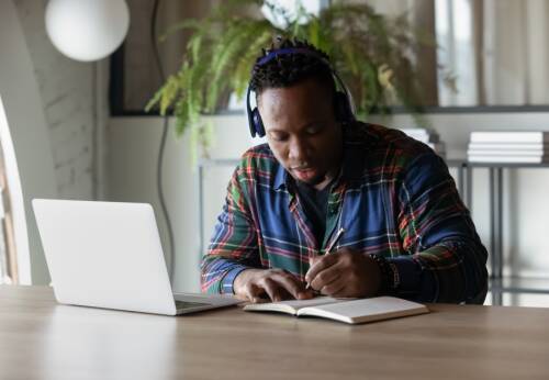 Student working at a desk with a laptop, wearing headphones